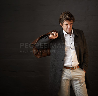 Buy stock photo Shot of a well dressed businessman carrying a bag against a dark background