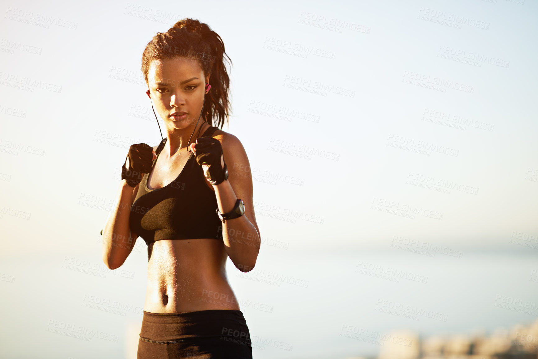 Buy stock photo Woman, portrait and boxer with earphones in nature for fitness, self defense or outdoor training. Active female person with gloves for morning workout, exercise or cardio by ocean coast in sunrise