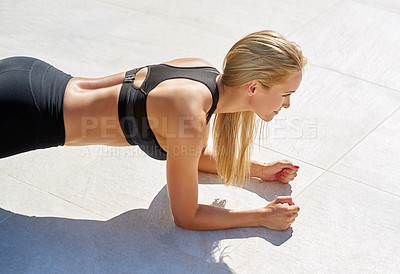 Buy stock photo Cropped shot of a young woman doing a plank exercise outside