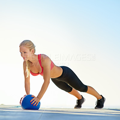 Buy stock photo Full length shot of a young woman doing pushups with a medicine ball