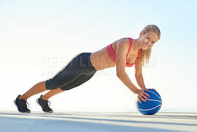 Buy stock photo Full length portrait of a young woman doing pushups with a medicine ball