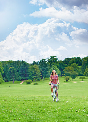 Buy stock photo Shot of a young woman cycling in the countryside