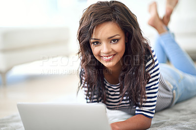 Buy stock photo Portrait of a young woman using her laptop while lying on the floor
