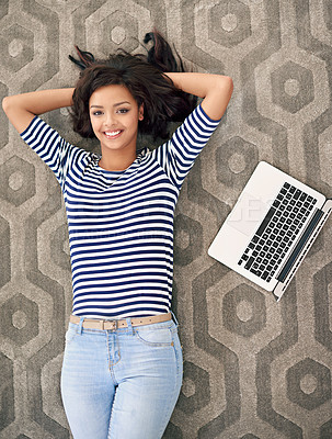 Buy stock photo High angle portrait of a young woman lying beside her laptop on the floor