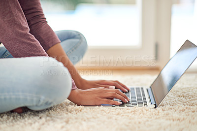 Buy stock photo Shot of an unrecognizable woman using her laptop while sitting on the floor