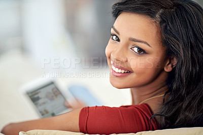 Buy stock photo High angle portrait of a young woman using her tablet while relaxing at home