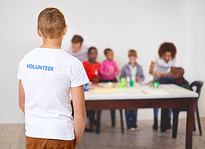 Buy stock photo Rearview shot of a volunteer watching other volunteers working with little children in the background
