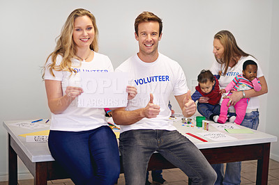 Buy stock photo Portrait of volunteers holding up a blank sign while working with little children