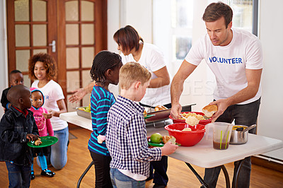 Buy stock photo Shot of volunteers serving food to a group of little children