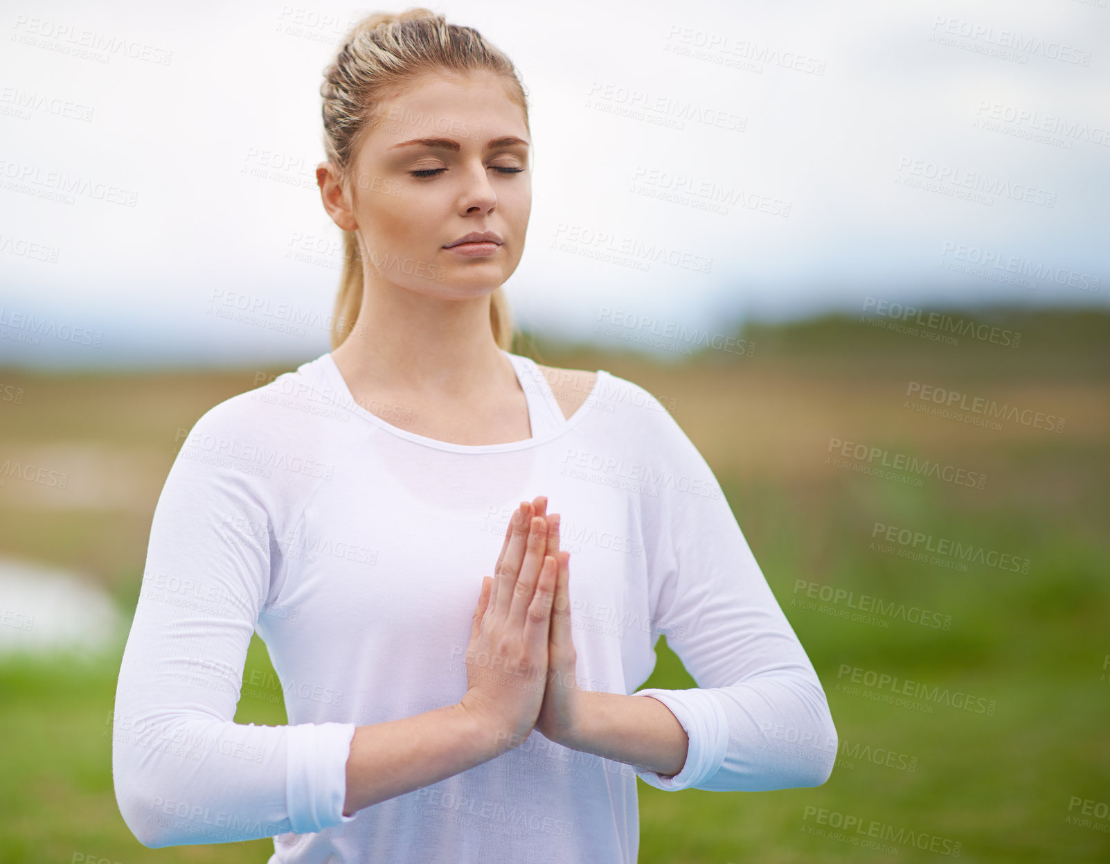 Buy stock photo Shot of a young woman doing yoga in the outdoors