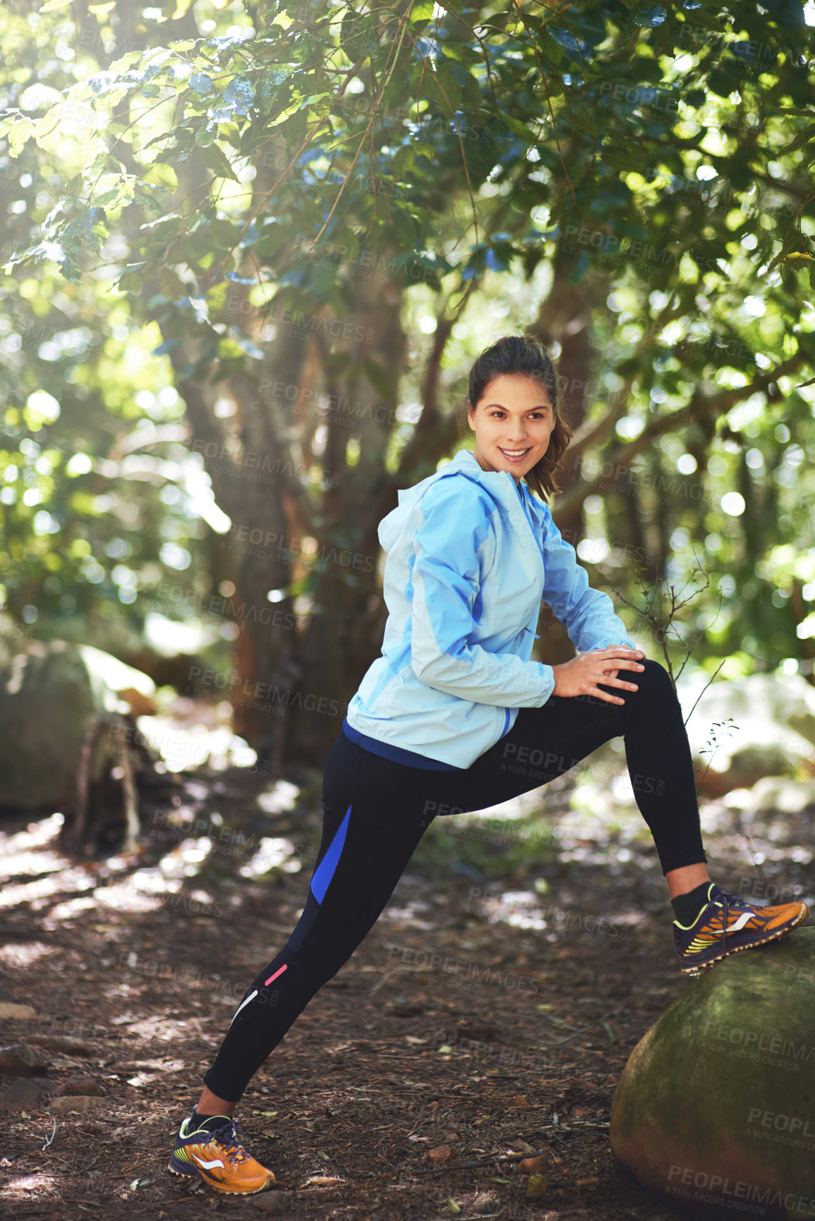 Buy stock photo Shot of a young woman stretching before a trail run