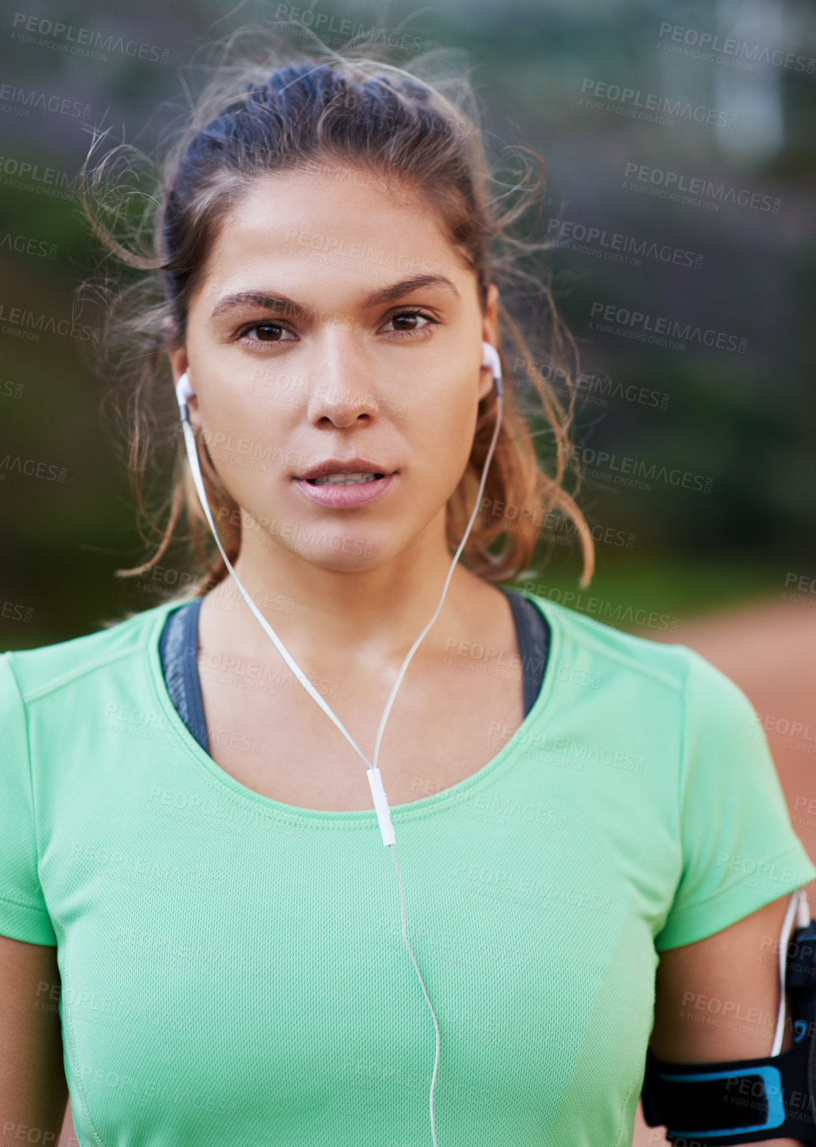 Buy stock photo Shot of a young woman listening to music while out running