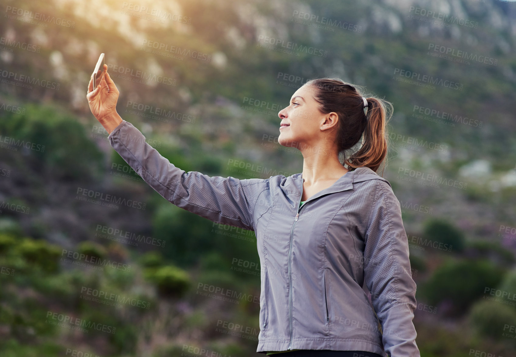 Buy stock photo Shot of a young woman taking a selfie while out for a trail run