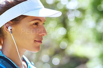 Buy stock photo Closeup shot of woman listening to music on earphones while out for a trail run