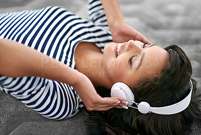 Buy stock photo Shot of a young woman listening to music at home