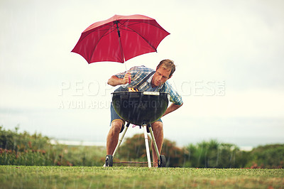 Buy stock photo Shot of a man trying to barbeque in the rain