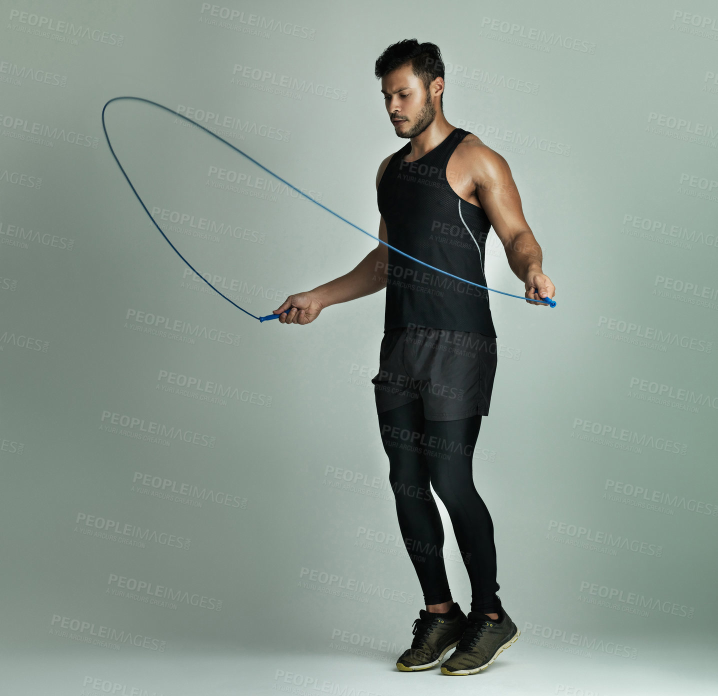 Buy stock photo Studio shot of a young man skipping with a jump rope against a gray background