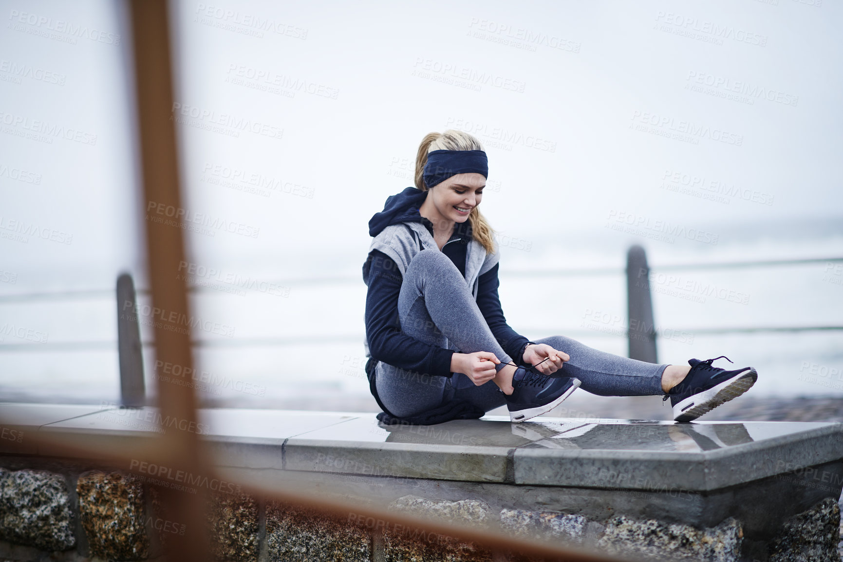 Buy stock photo Shot of a young woman tying her shoelaces before a run