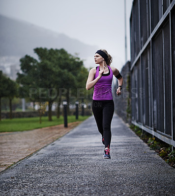 Buy stock photo Shot of a young woman running along a path