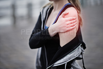 Buy stock photo Cropped shot of a young woman holding her injured shoulder