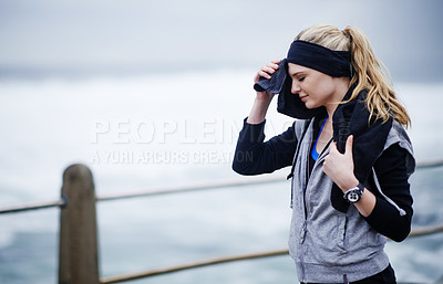 Buy stock photo Shot of a young woman wiping her forehead with a towel after a run