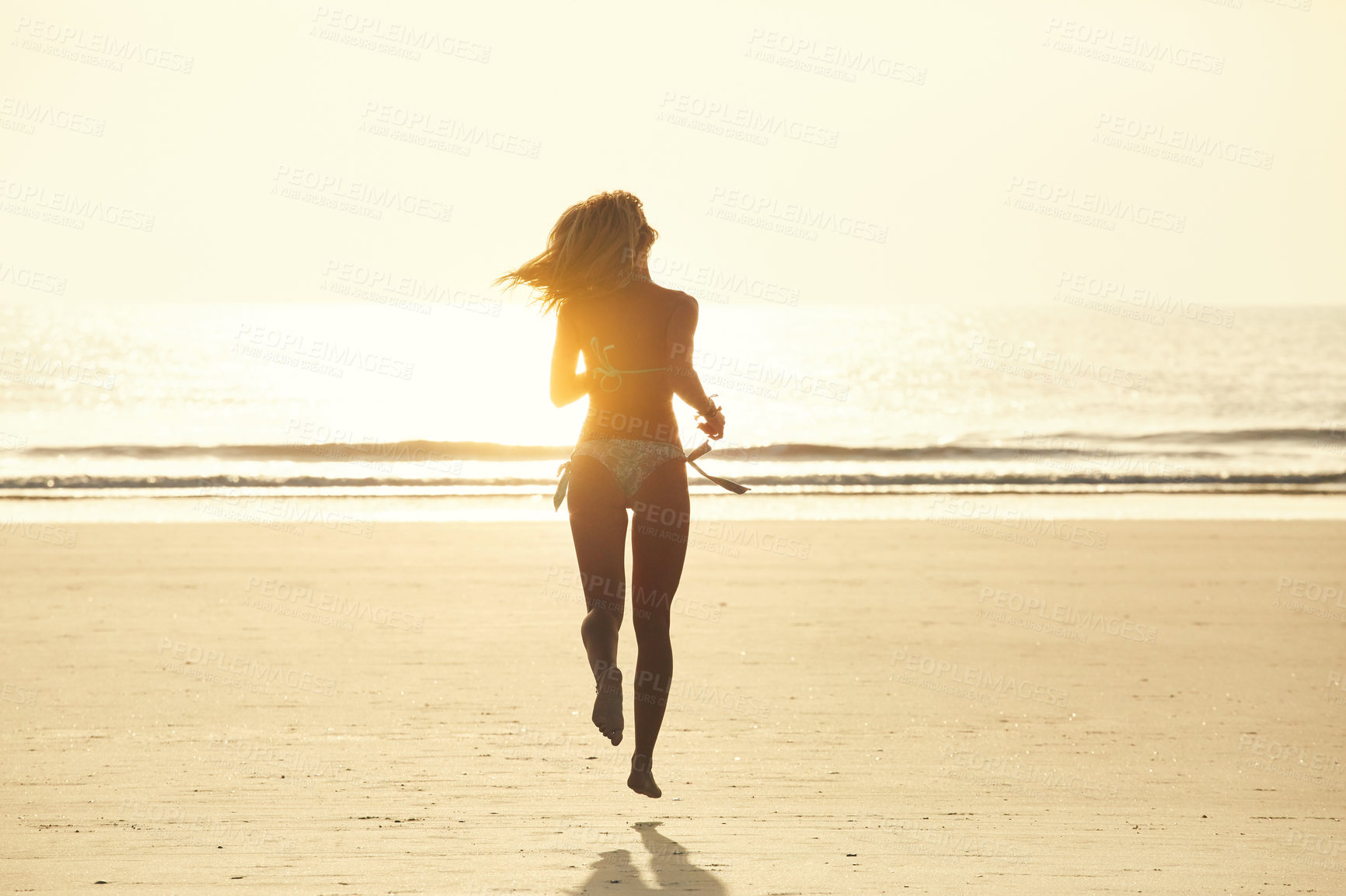 Buy stock photo Rearview shot of an attractive young woman running on the beach
