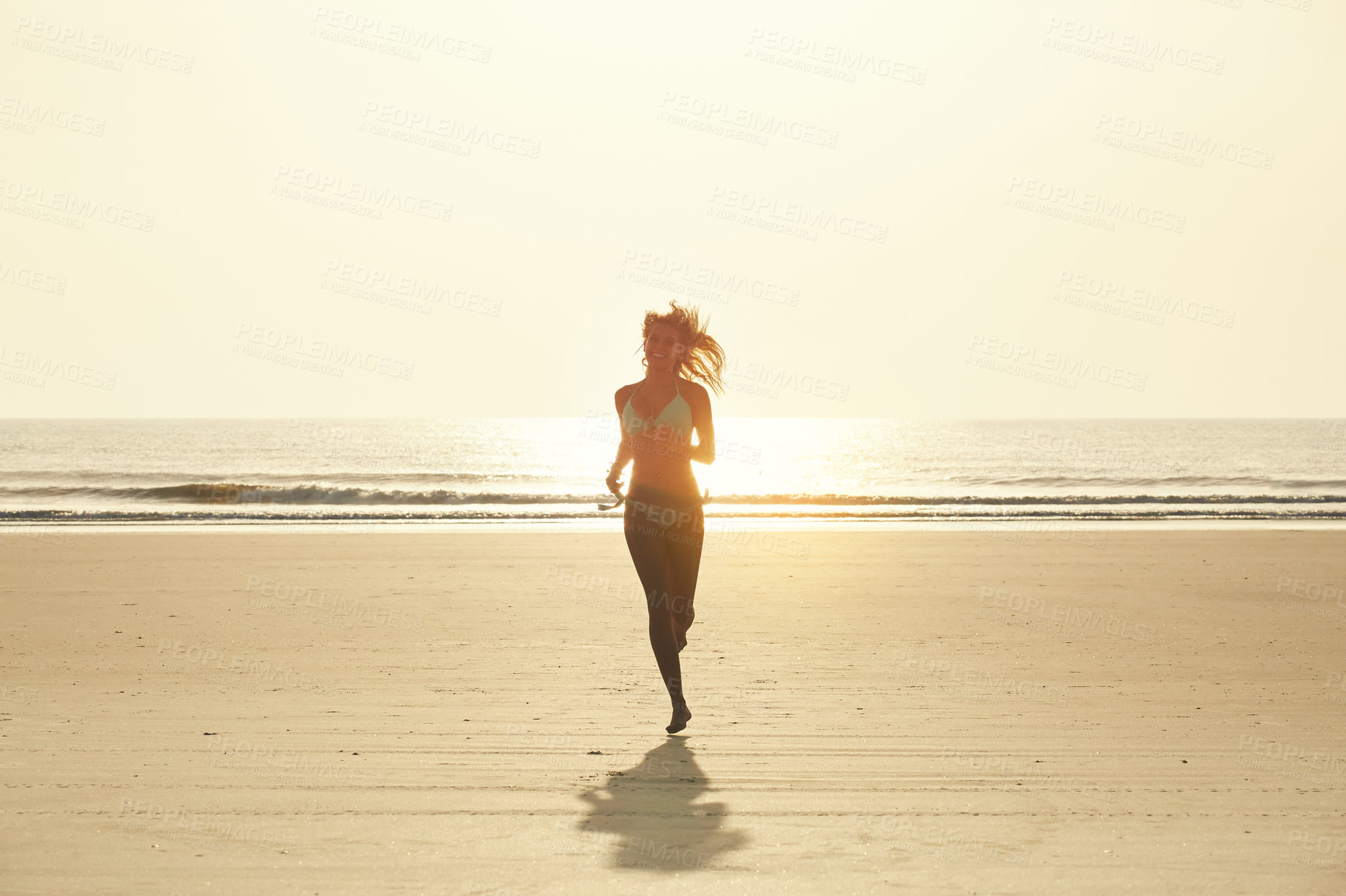 Buy stock photo Portrait of an attractive young woman running on the beach