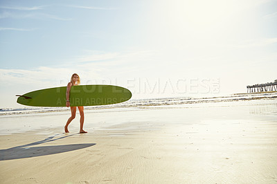 Buy stock photo Shot of an attractive young woman carrying her surfboard on the beach