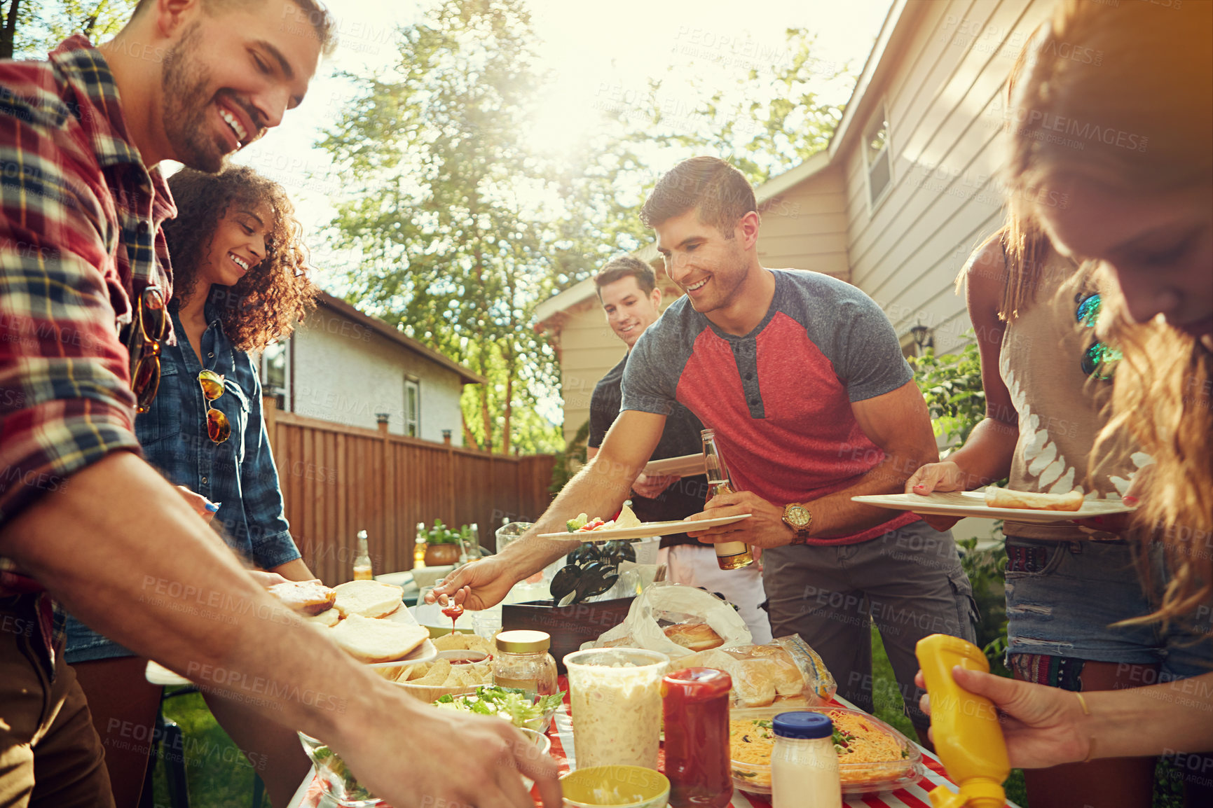 Buy stock photo Shot of a group of friends having lunch in their backyard