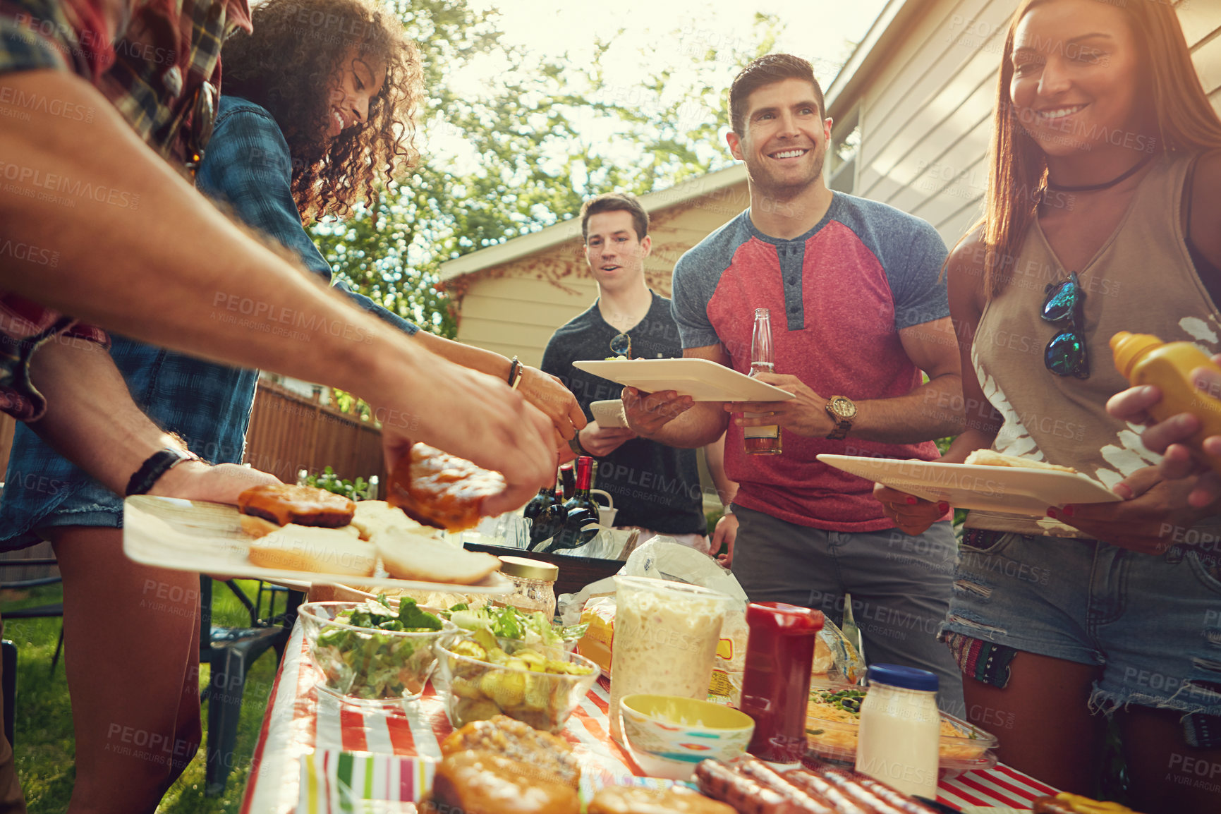 Buy stock photo Shot of a group of friends having lunch in their backyard