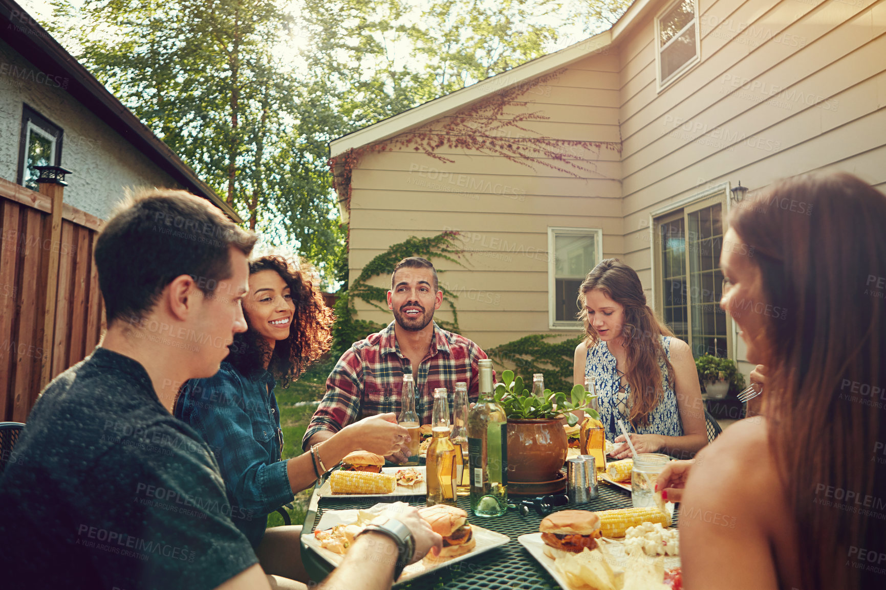Buy stock photo Shot of a group of friends having lunch in their backyard