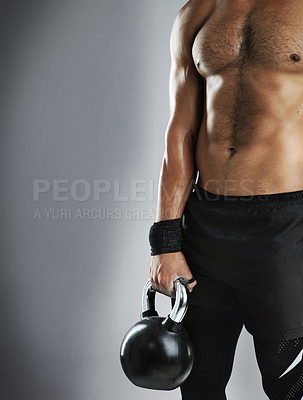 Buy stock photo Cropped studio shot of a fit young man working out with a kettle bell