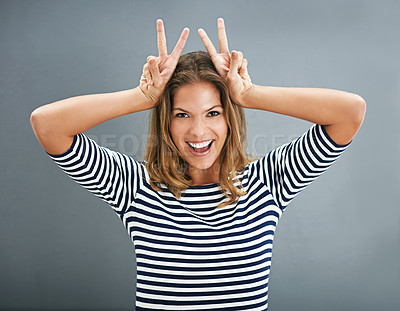 Buy stock photo Woman, bunny ears and fingers in studio portrait, funny sign and play on gray background. Female person, emoji and rabbit icon or symbol for comedy, comic gesture and mockup space for easter humor