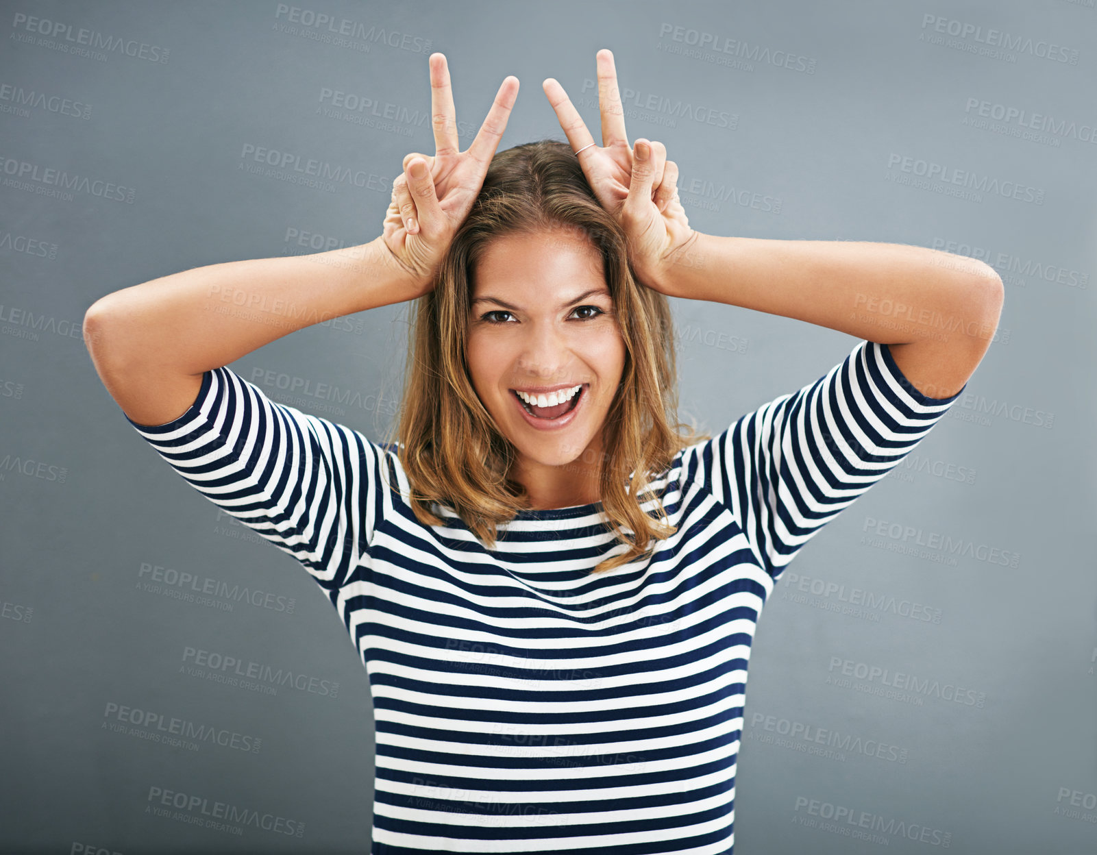 Buy stock photo Woman, bunny ears and fingers in studio portrait, funny sign and play on gray background. Female person, emoji and rabbit icon or symbol for comedy, comic gesture and mockup space for easter humor