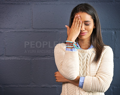 Buy stock photo Shot of a young woman covering her eye against a brick wall background
