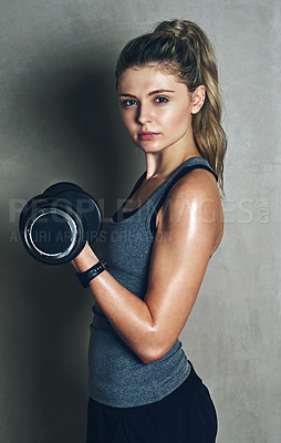 Buy stock photo Shot of a young woman lifting dumbbells against a gray background