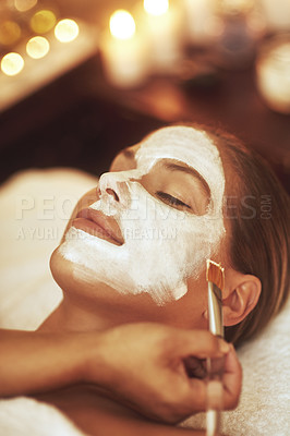 Buy stock photo Woman, face mask and treatment with brush for spa holiday or skincare beautician, stress relief or dermatology. Female person, hand and facial with candle bokeh at Bali resort, self care or hotel