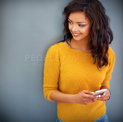 Buy stock photo Studio shot of a young woman using her phone against a gray background