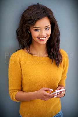 Buy stock photo Studio portrait of a young woman using her phone against a gray background