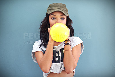 Buy stock photo Studio shot of a young woman inflating a balloon against a teal background