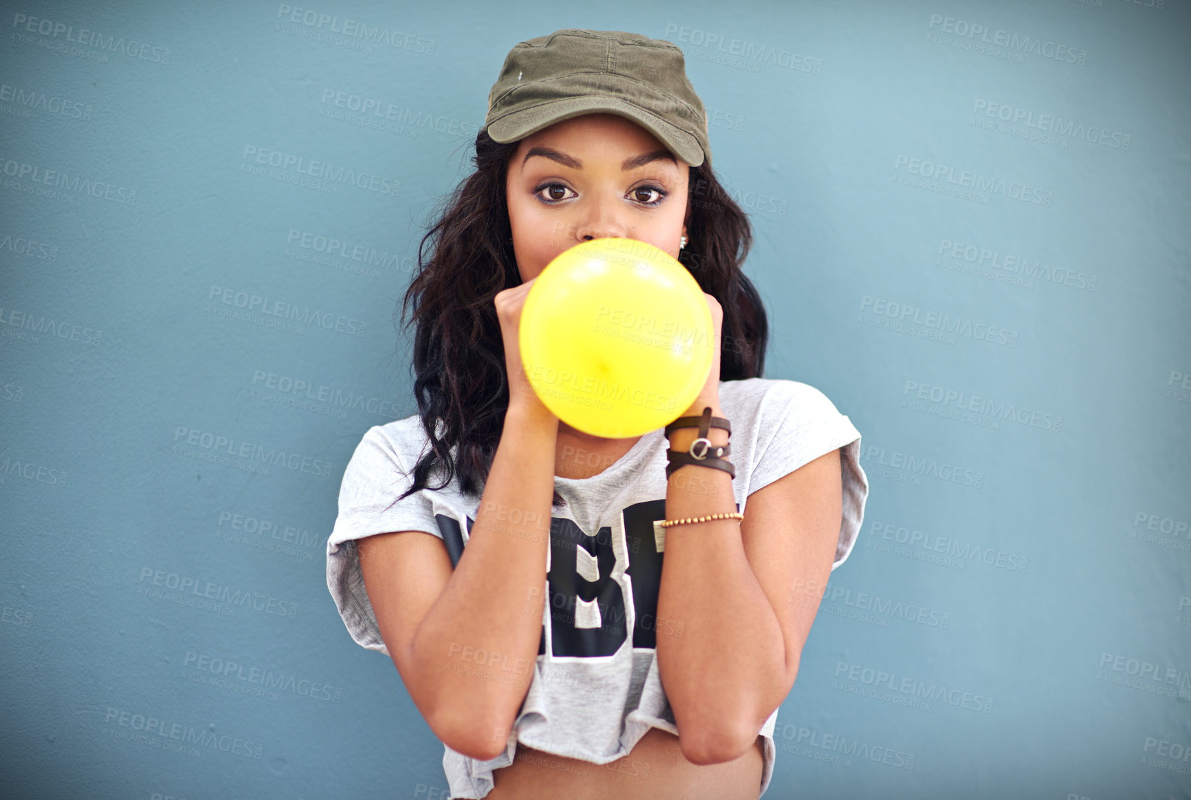 Buy stock photo Studio shot of a young woman inflating a balloon against a teal background