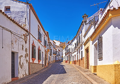 Buy stock photo Buildings, town and alley outside with architecture, travel and exploration with blue sky or aesthetic. Infrastructure, village and street outdoor for holiday, vacation and tourist location in Spain