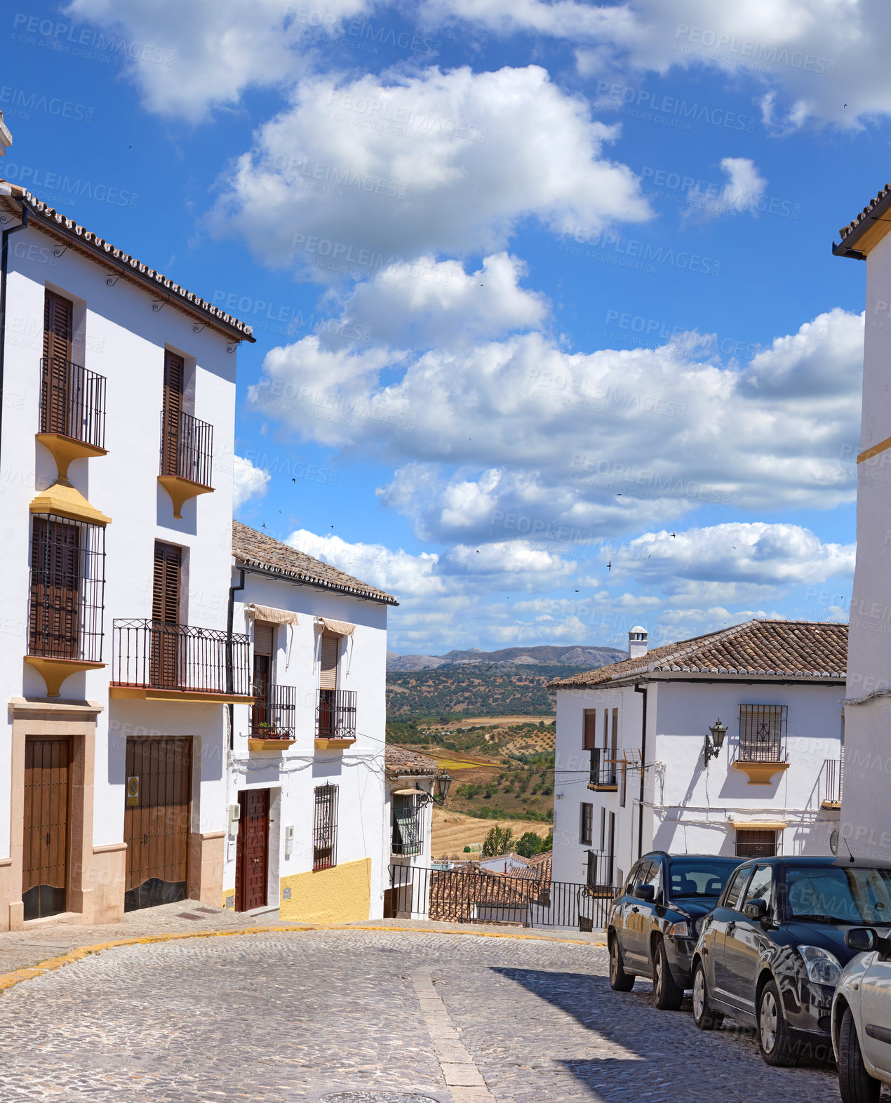 Buy stock photo Cobblestone, road and cars by houses for architecture, buildings and travel or landscape in Spain. Ronda, old city and whitewash homes for heritage, history and village design in Europe for aesthetic