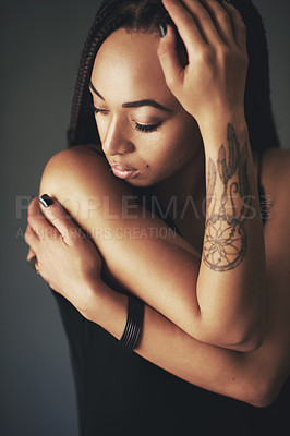 Buy stock photo Studio shot of a beautiful young woman with a tattoo on her arm against a gray background