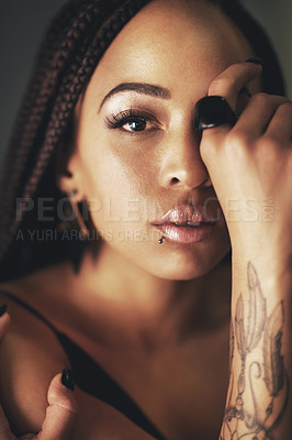 Buy stock photo Studio portrait of a beautiful young woman with a tattoo on her arm against a gray background