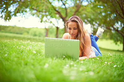 Buy stock photo Shot of a young woman using her laptop at the park