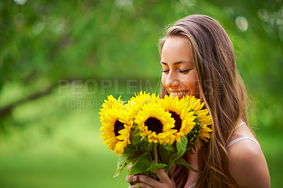 Buy stock photo Shot of a young woman holding a bunch of sunflowers outside