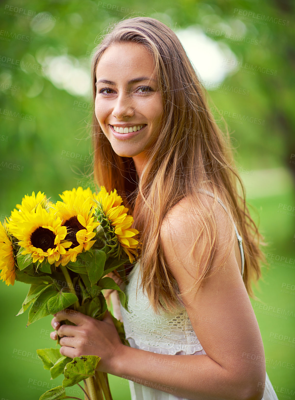 Buy stock photo Shot of a young woman holding a bunch of sunflowers outside