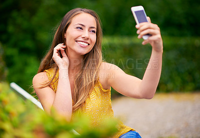 Buy stock photo Shot of a carefree young woman taking a selfie on her phone at the park
