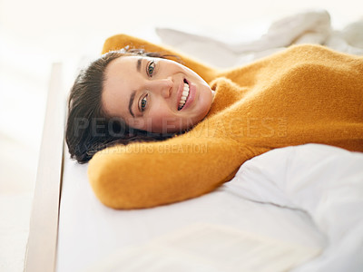 Buy stock photo Cropped portrait of a young woman lying on her bed